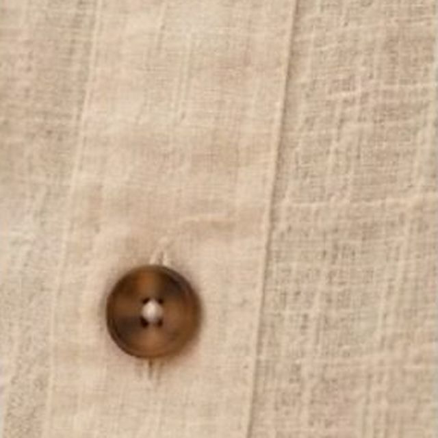 A horn button on textured ecru linen